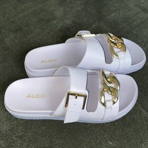 Lavender Aldo slide sandals with gold chain.
